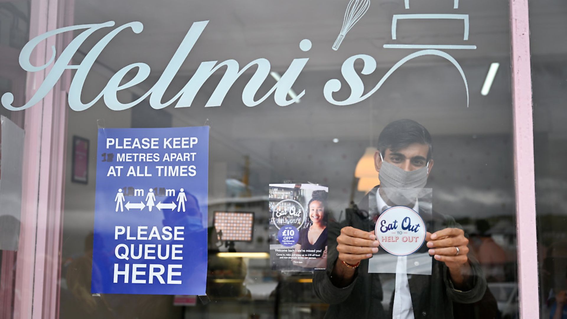Chancellor of the Exchequer Rishi Sunak places an Eat Out to Help Out sticker in the window of a business during a visit to Rothesay on the Isle of Bute, Scotland; Jeff J Mitchell - Credit: PA
