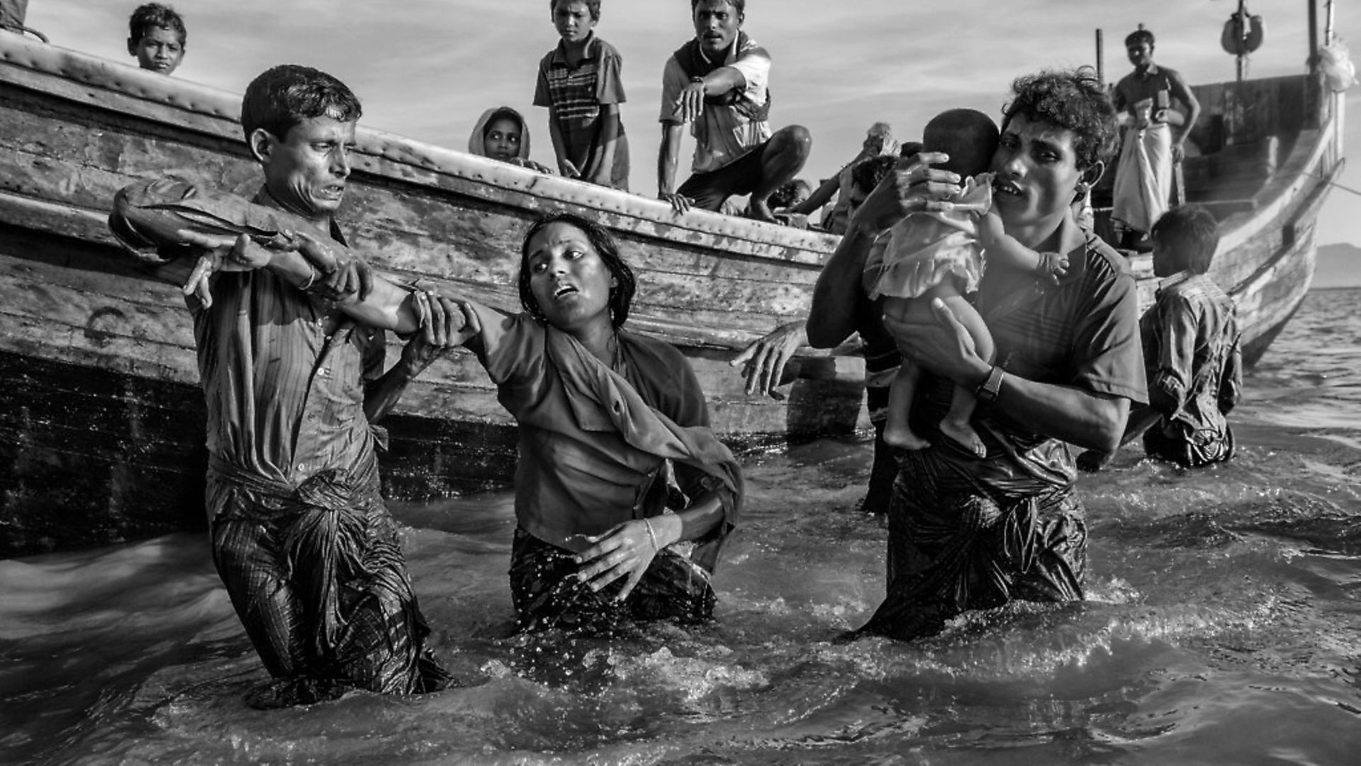COX'S BAZAR, BANGLADESH - OCTOBER 01: Shikira Arifullah, a 22-year-old Rohingya refugee woman from Guddumpara village, is helped from a boat as she arrives exhausted on the Bangladesh side of the Naf River at Shah Porir Dwip after fleeing her village in Myanmar, on October 1, 2017 in Cox's Bazar, Bangladesh. More than half a million Rohingya refugees have flooded into Bangladesh to flee an offensive by Myanmar's military that the United Nations has called 'a textbook example of ethnic cleansing'.  The refugee population is expected to swell further, with thousands more Rohingya Muslims said to be making the perilous journey on foot toward the border, or paying smugglers to take them across by water in wooden boats. Hundreds are known to have died trying to escape, and survivors arrive with horrifying accounts of villages burned, women raped, and scores killed in the 'clearance operations' by Myanmar's army and Buddhist mobs that were sparked by militant attacks on security posts in Rakhine state on August 25, - Credit: Getty Images