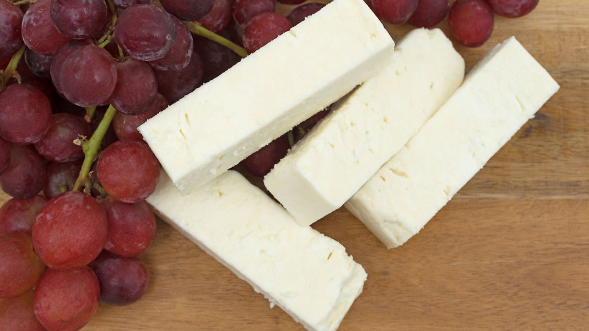 A generic photo of Close view of several large slices of feta cheese on a wood cheese board with a bunch of fresh red grapes. See PA Feature CHRISTMAS Food Swaps. Picture credit should read: PA Photo/thinkstockphotos. WARNING: This picture must only be used to accompany PA Feature CHRISTMAS Food Swaps - Credit: Archant