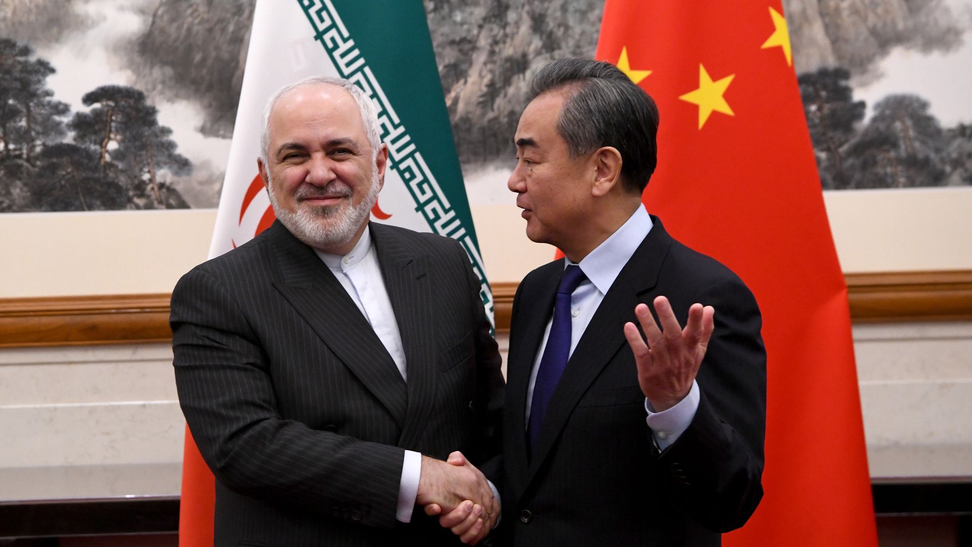 China's Foreign Minister Wang Yi shakes hands with Iran's Foreign Minister Mohammad Javad Zarif during a meeting at the Diaoyutai state guest house. - Credit: Getty Images