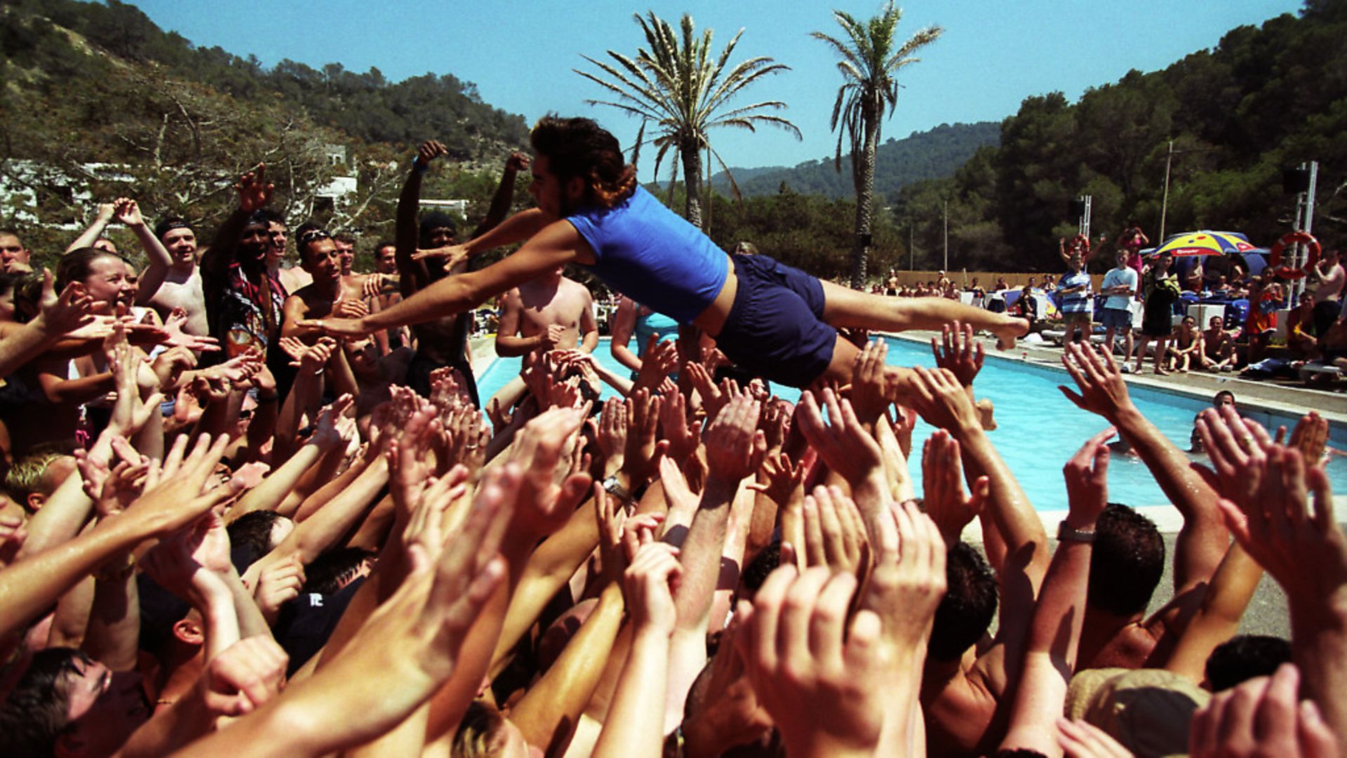 A holiday rep diving into a crowd of people, at a pool party, Club 18-30 Ibiza, 2001. (Photo by: PYMCA/Universal Images Group via Getty Images) - Credit: Universal Images Group via Getty