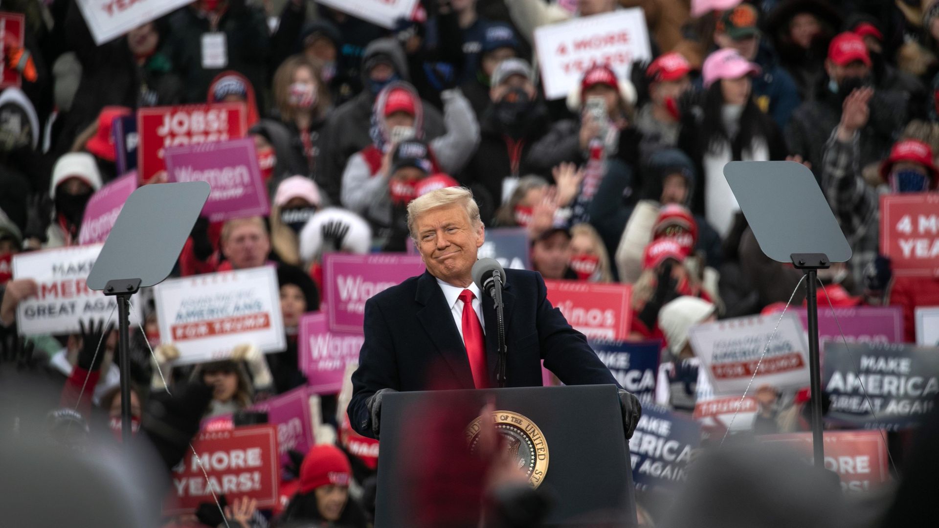 President Donald Trump smiles while disparaging Democratic presidential nominee Joe Biden at a campaign rally at Oakland County International Airport - Credit: Getty Images