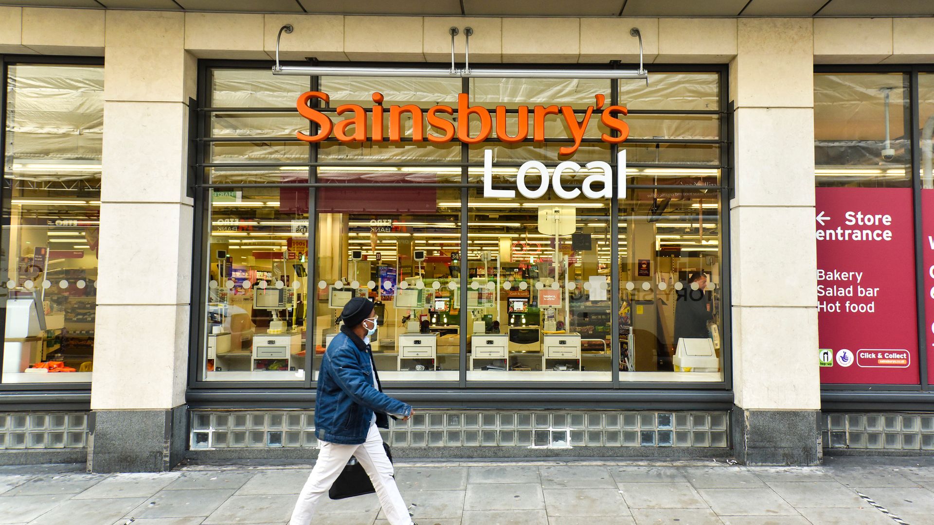 A man wearing a face mask walks past the Sainsburys shop in Holborn, London as the company announces it is cutting 3,500 jobs and closing 420 Argos stores - Credit: SOPA Images/LightRocket via Gett