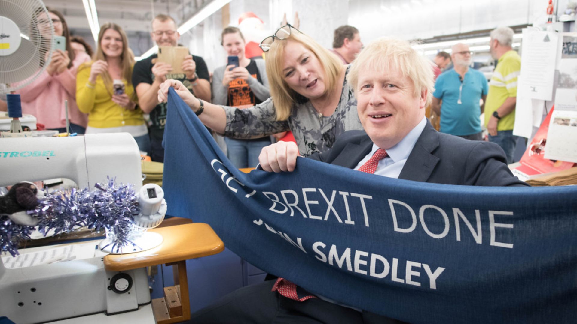 Prime Minister Boris Johnson holds up a banner with the words 'Get Brexit Done' during a visit to the John Smedley Mill - Credit: PA