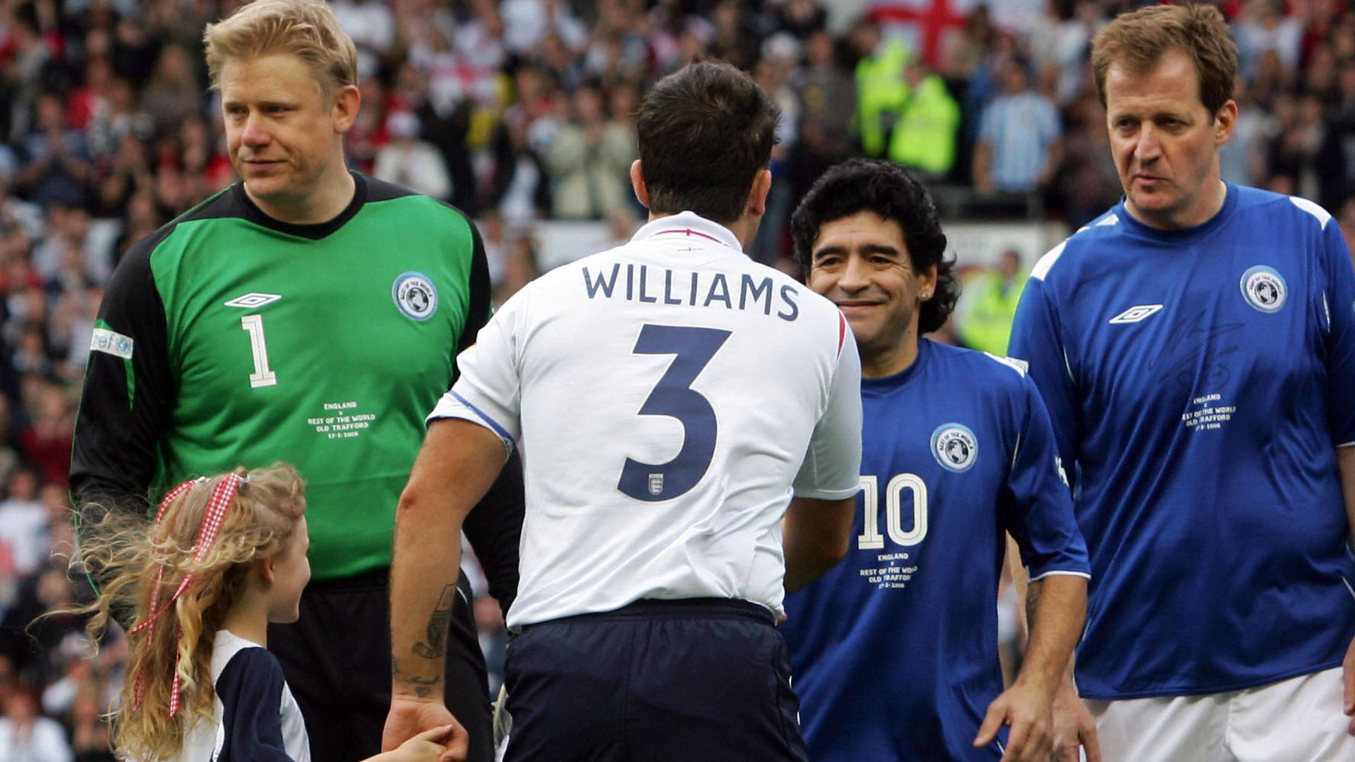 Diego Maradona, lining up alongside Alastair Campbell (r) and  Peter Schmeichel (l), greets Robbie Williams at the start of the Soccer Aid charity match at Old Trafford, in 2006 - Credit: AFP via Getty Images