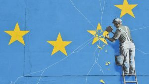 A mural by British artist Banksy, depicting a workman chipping away at one of the stars on a European Union (EU) themed flag - Credit: AFP via Getty Images