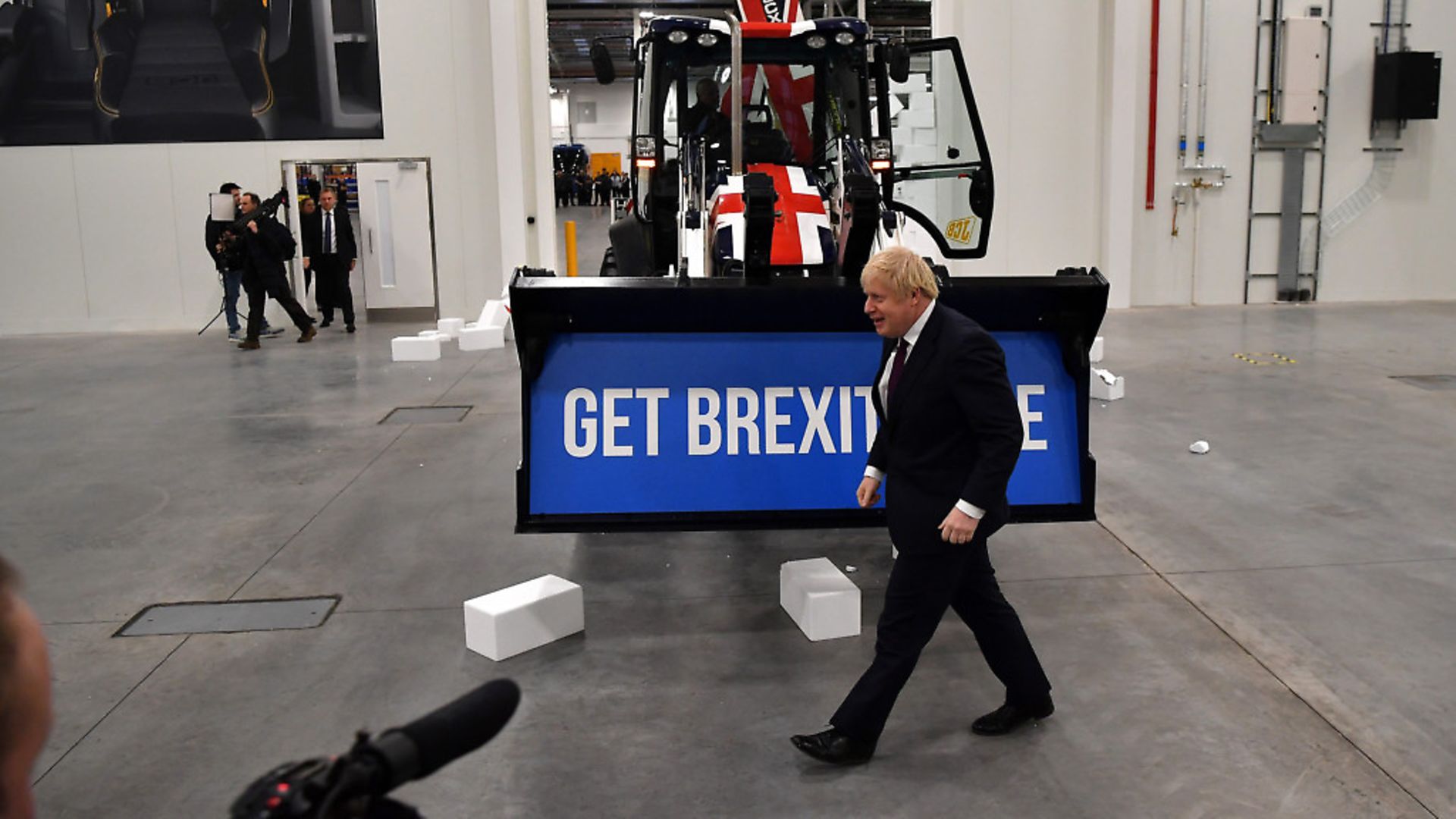 Boris Johnson walks past a Union flag-themed JCB, after driving it through a fake wall emblazoned with the word "GRIDLOCK", during a general election campaign event at JCB construction company. (Photo by Ben Stansall - WPA Pool/Getty Images) - Credit: Getty Images
