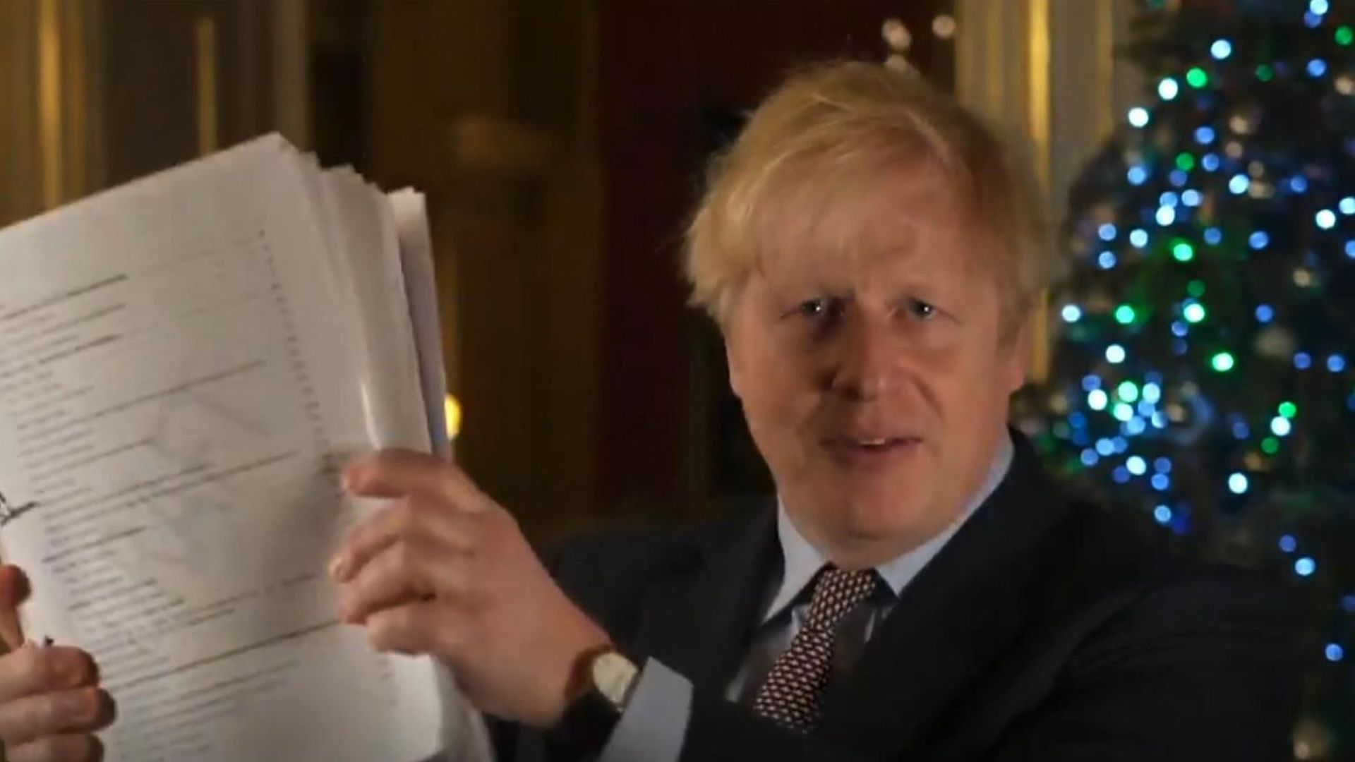 Boris Johnson holds up his Brexit agreement in a Christmas message - Credit: Twitter