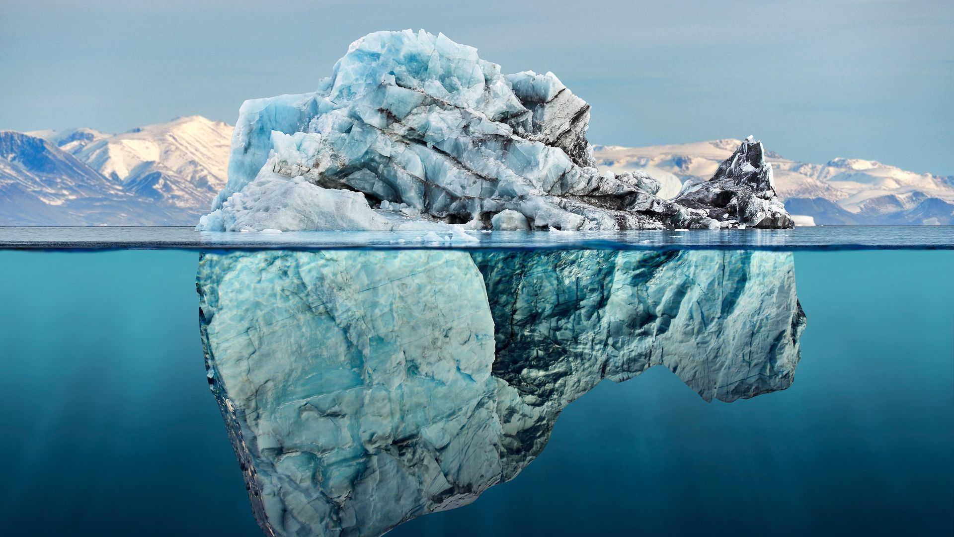 An iceberg seen above and below the water, off the coast of Greenland - Credit: Getty Images