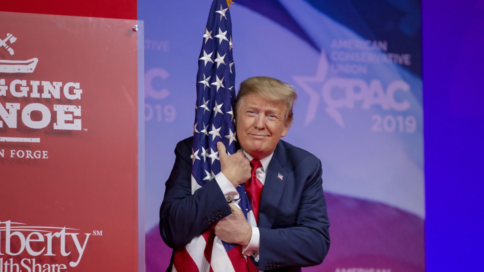 U.S. President Donald Trump hugs the U.S. flag - Credit: Getty Images