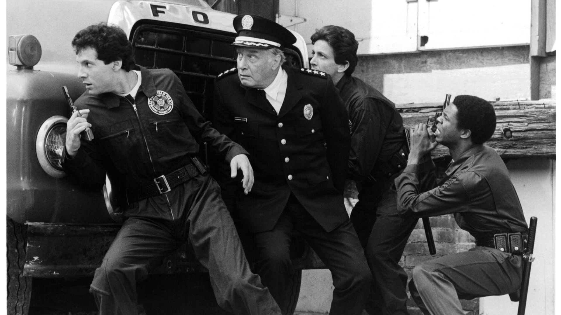 George Gaynes (centre), as Commandant Lassard, with Steve Guttenberg, Andrew Rubin and Michael Winslow in a scene from the 1984 film 'Police Academy' - Credit: Getty Images