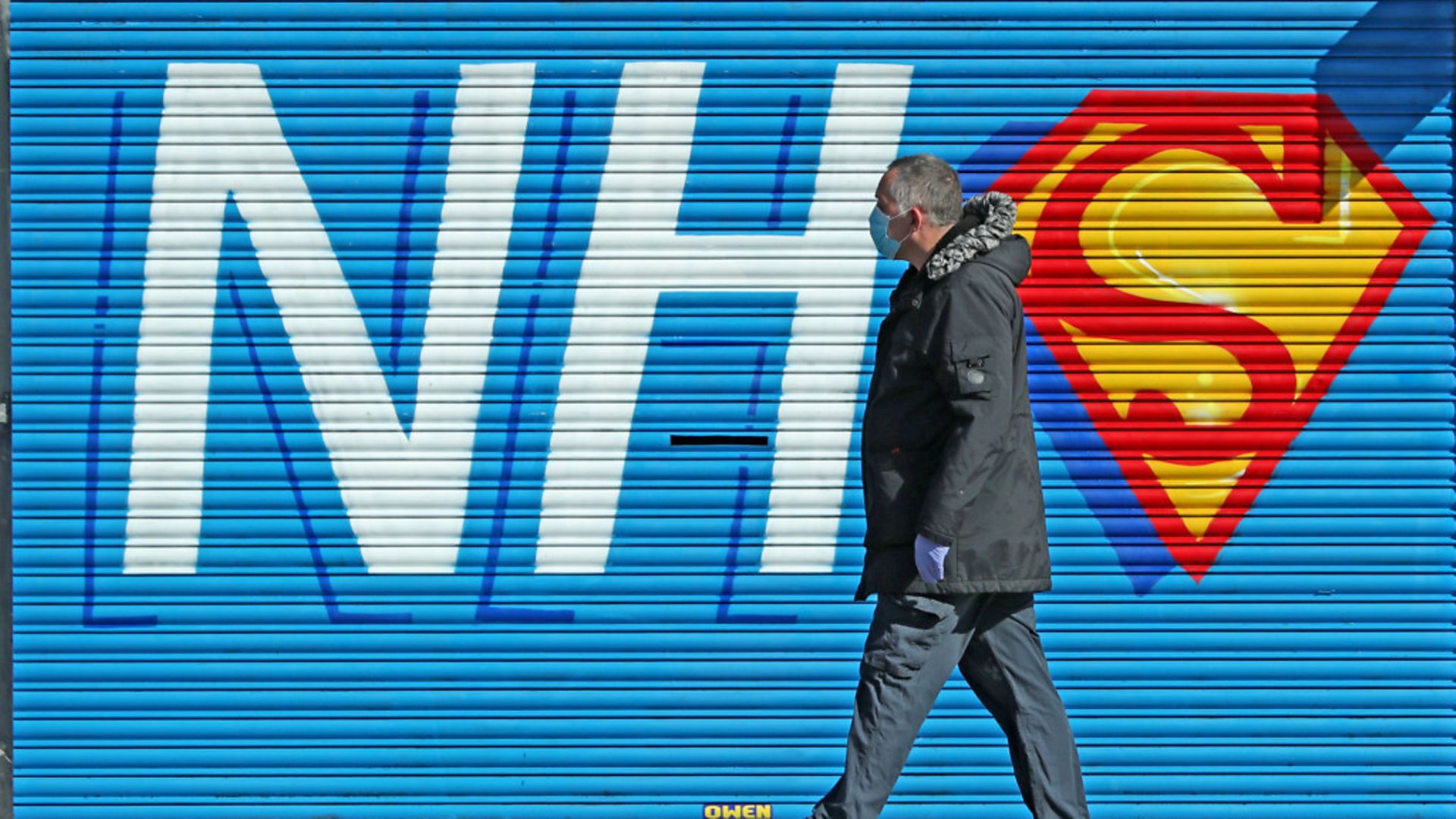 A man walks past a sign created in support of the NHS during the pandemic - Credit: Peter Byrne/PA