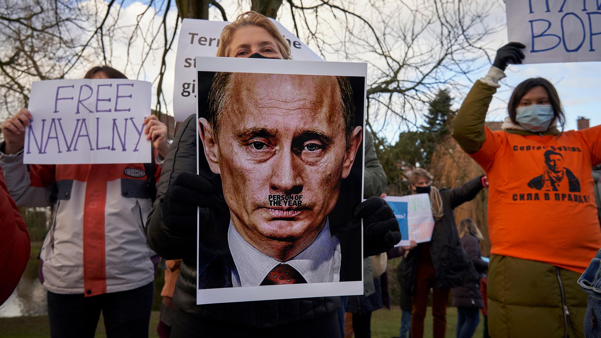 Demonstrators hold up banners in front of the Russian embassy in The Hague, Netherlands - Credit: Getty Images