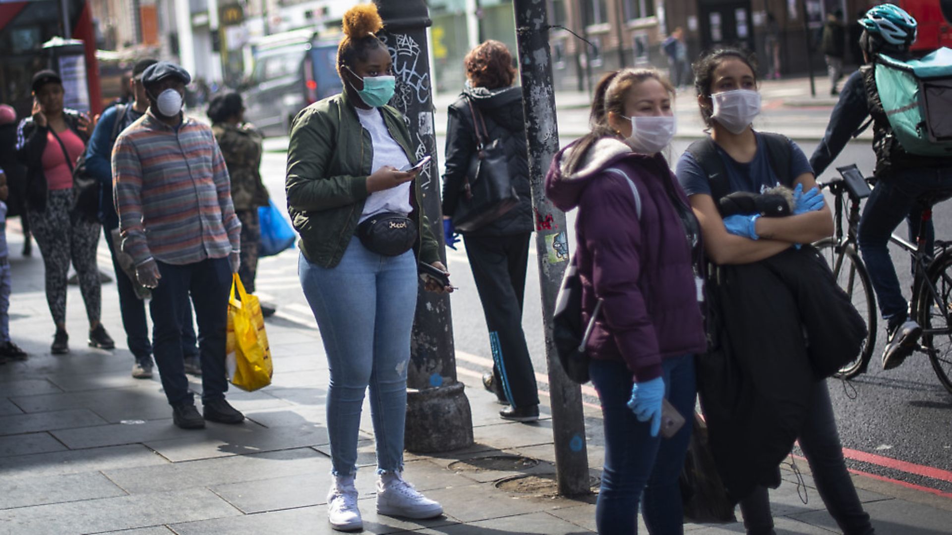 People wearing protective face masks wait in line for a supermarket in Brixton, South London, as the UK continues in lockdown to help curb the spread of the coronavirus. Photograph: Victoria Jones/PA Wire - Credit: PA