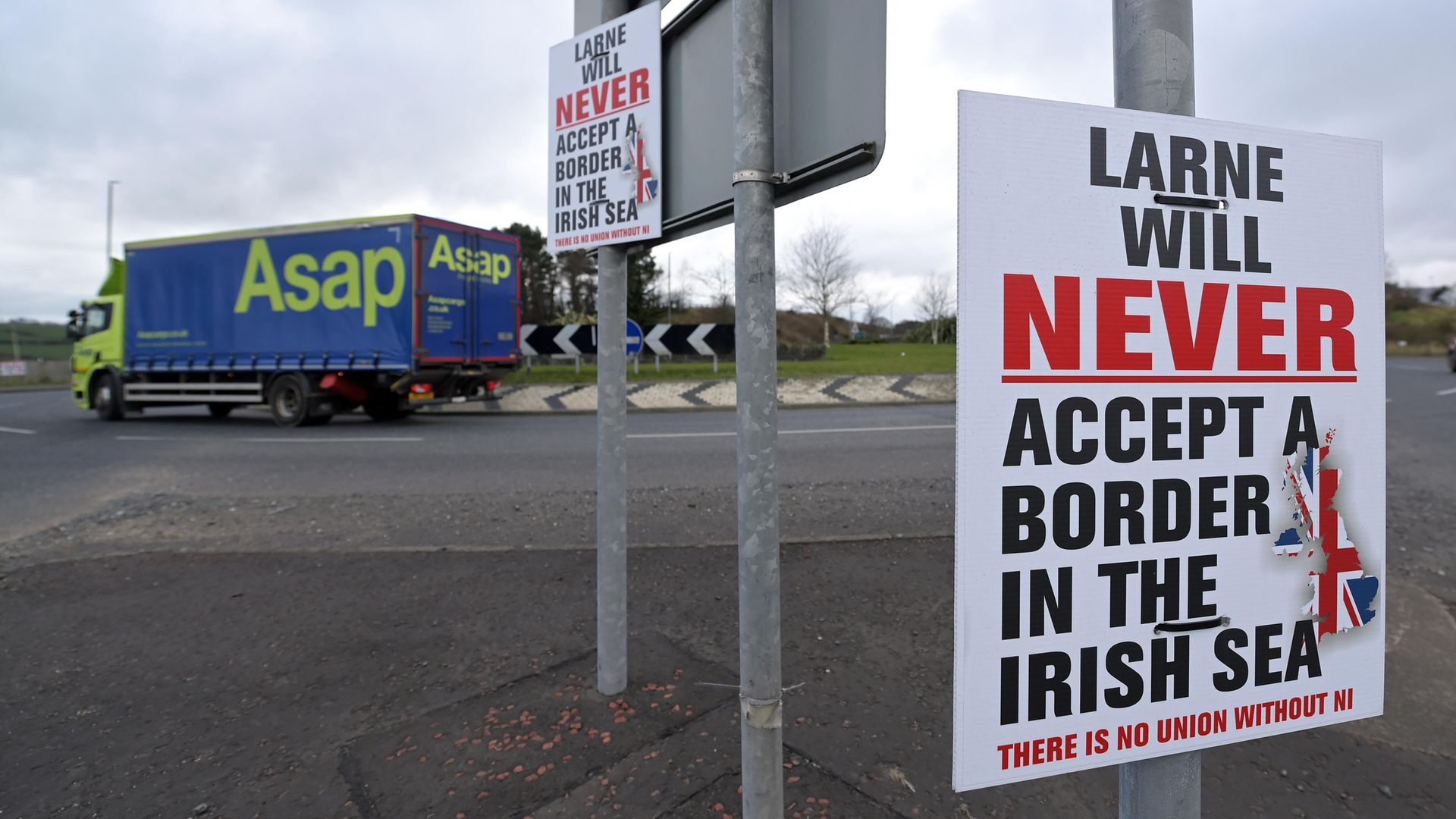 Freight arriving on the Cairnryan to Larne ferry passes a poster erected by Unionists against the Northern Ireland Protocol near Larne harbour - Credit: Getty Images