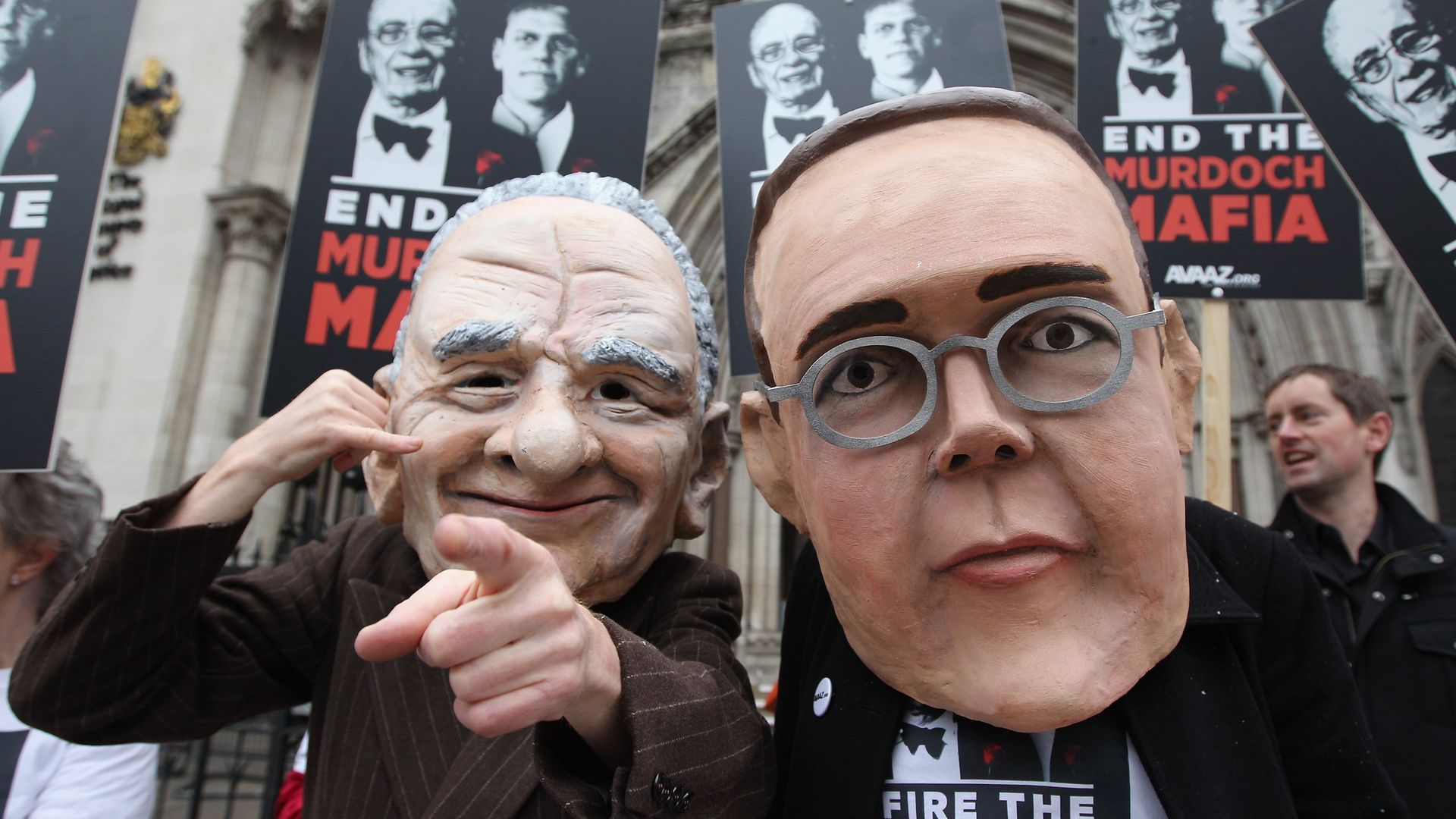 Protesters from the campaign group 'Avaaz' demonstrate outside the High Court with large James and Rupert Murdoch masks - Credit: Getty Images