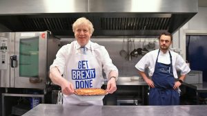 Prime Minister Boris Johnson holds a freshly baked pie while wearing a 'get Brexit done' apron. Photograph: Stefan Rousseau/PA.