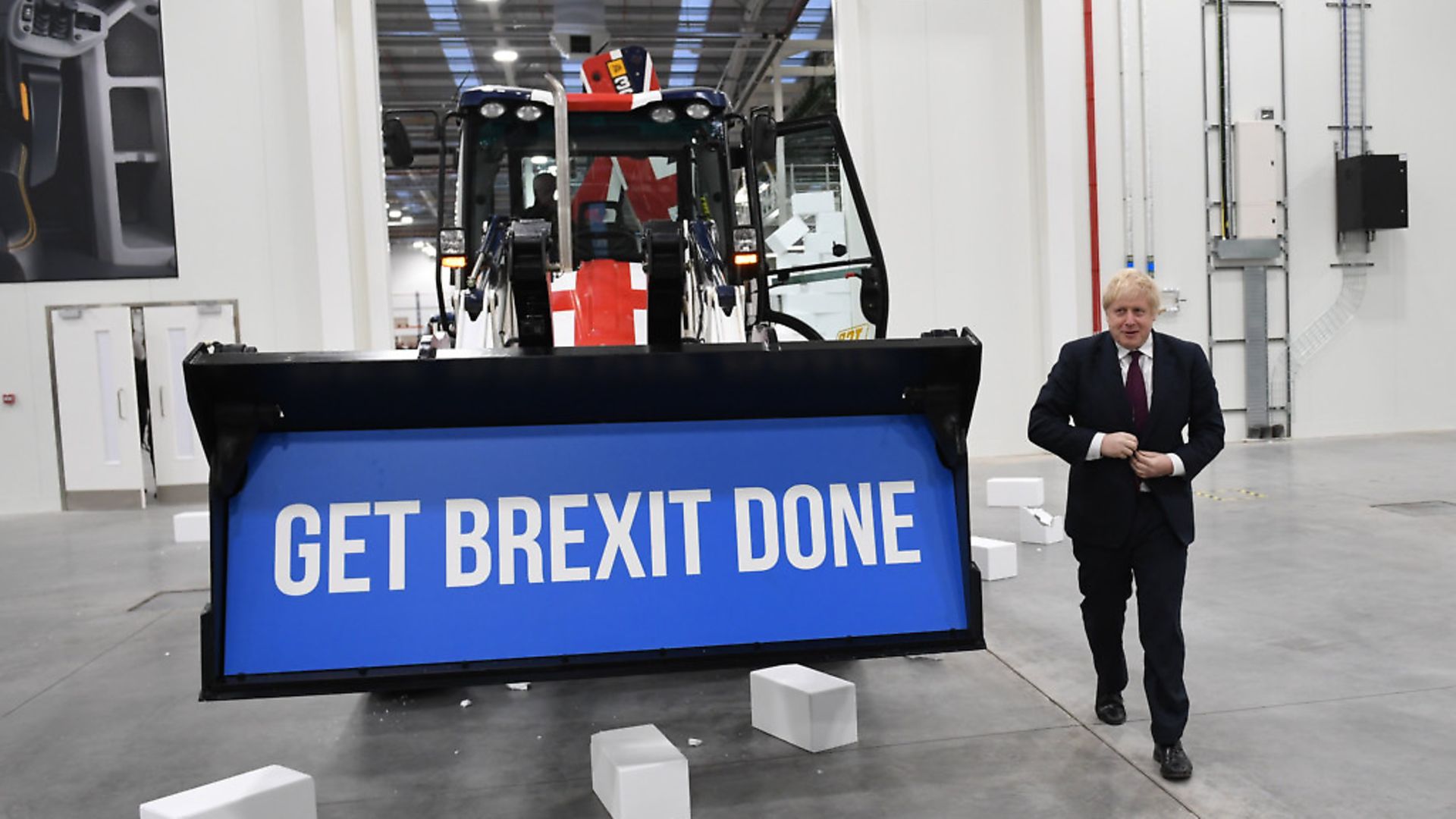 Prime Minister Boris Johnson walks away after driving a union flag-themed JCB, with the words "Get Brexit Done" inside the digger bucket. Photograph: Stefan Rousseau/PA. - Credit: PA Wire/PA Images
