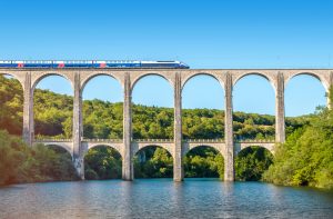 An SNCF train crosses the Cize-Bolozon viaduct bridge in Ain, Rhone-Alpes, France. The viaduct accommodates both road and rail. An original span, built in the same location in 1875, was destroyed in the Second World War. It was reconstructed as an urgent post-war project as it was on the main line to Paris.