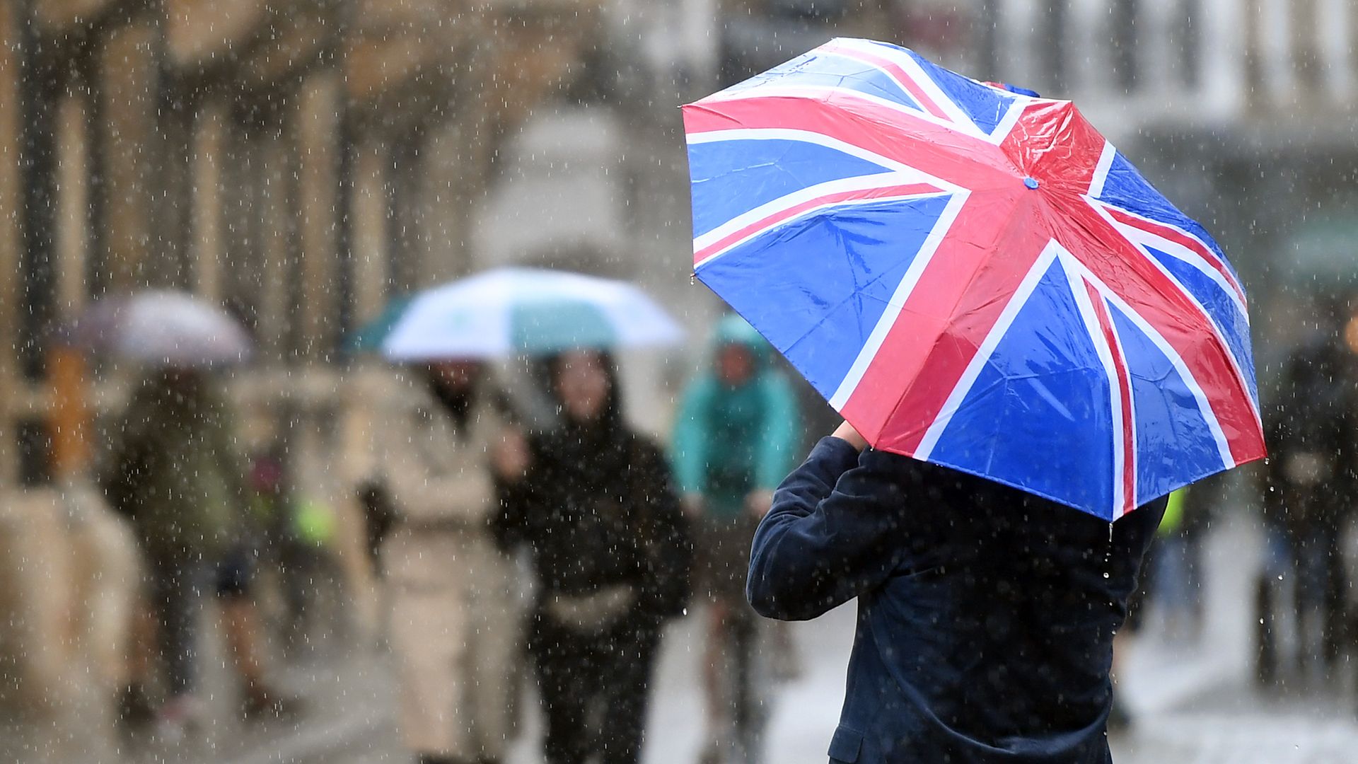 A man carries a Union flag umbrella - Credit: PA