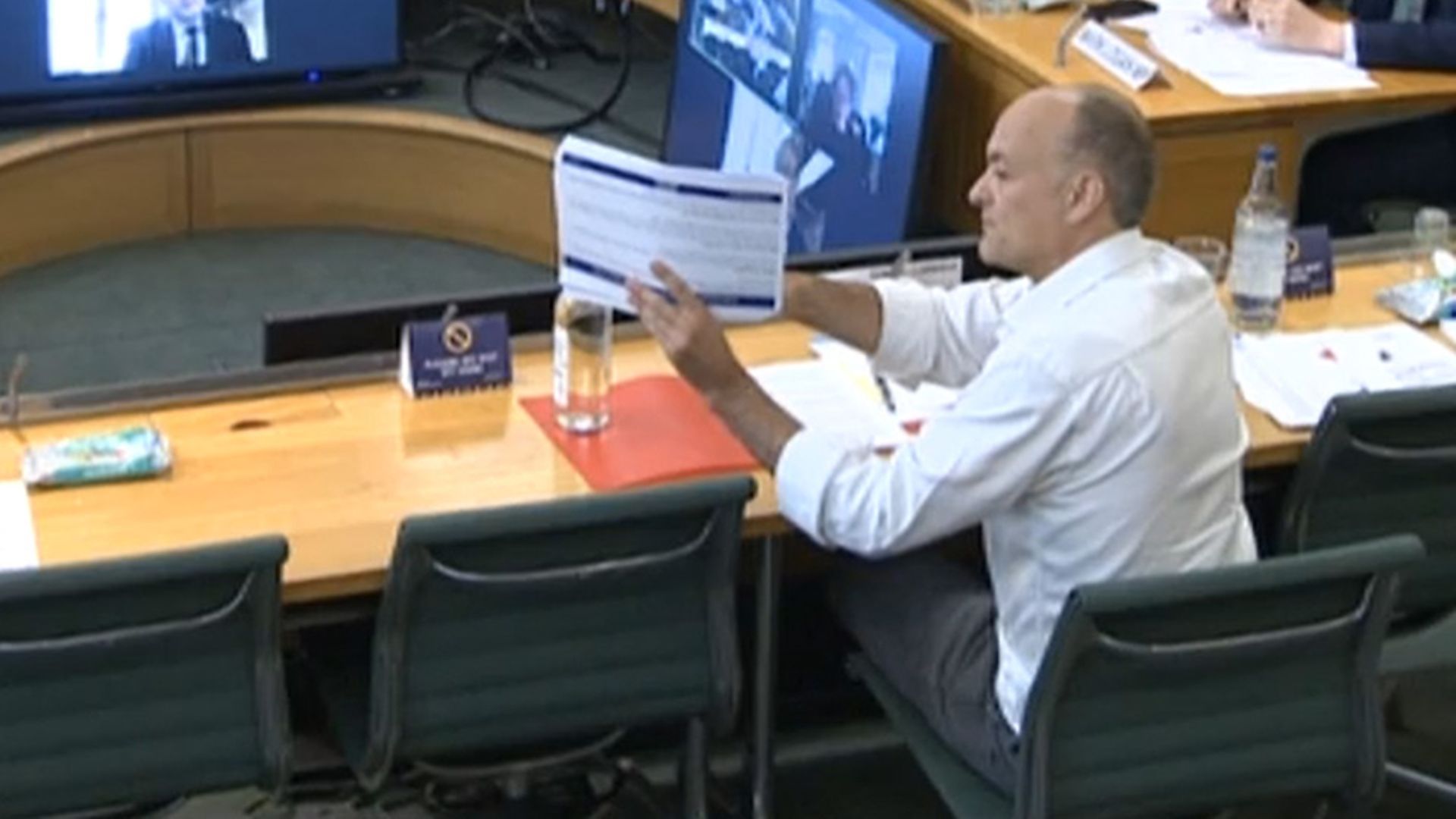 Dominic Cummings, former Chief Adviser to Prime Minister Boris Johnson, holds up a document whilst giving evidence to a joint inquiry of the Commons Health and Social Care and Science and Technology Committees - Credit: PA