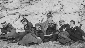 A group of holiday-makers sunning themselves on a south coast beach in 1895. Three of them have their noses in books - Credit: Express/Express/Getty Images
