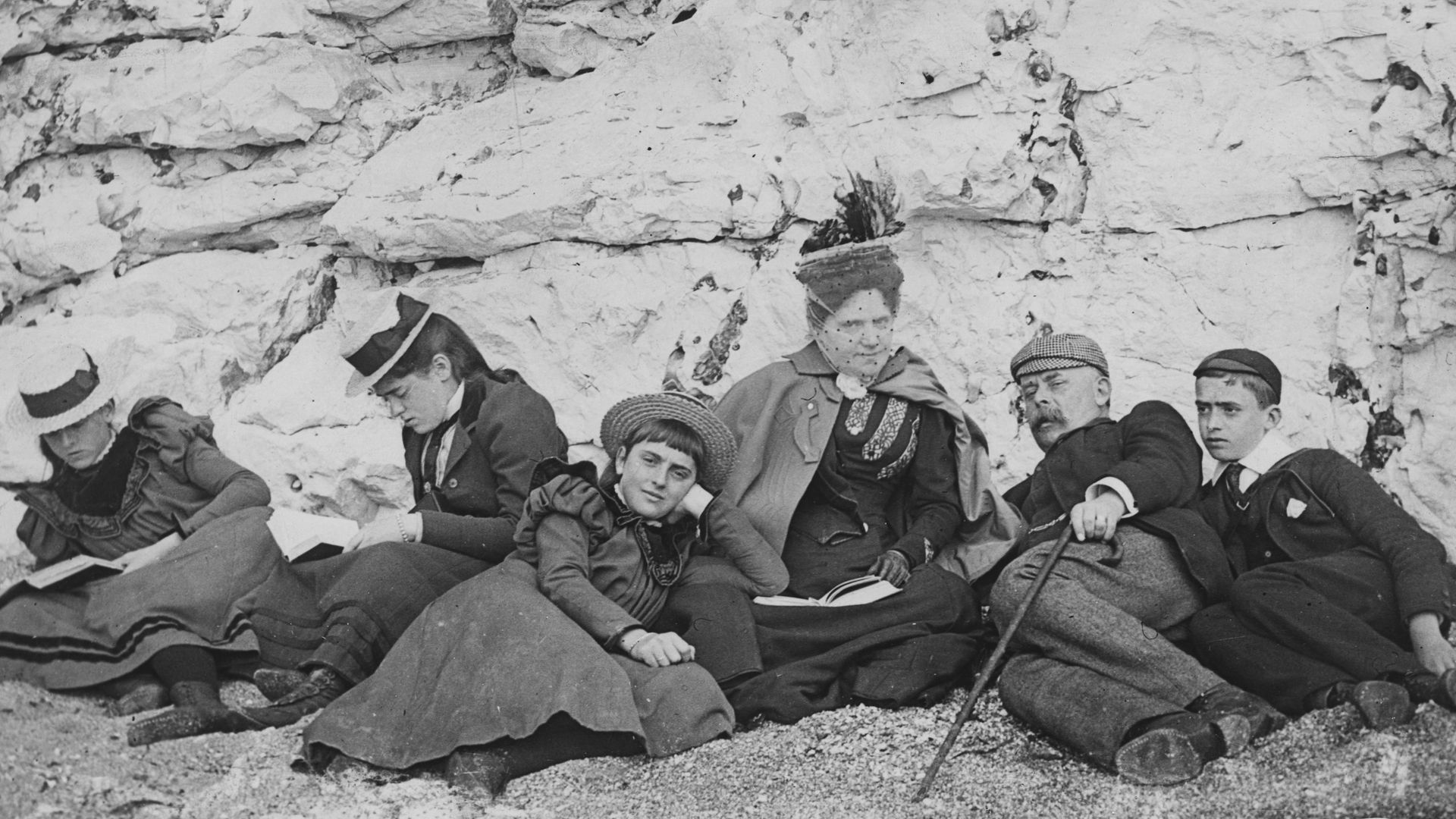 A group of holiday-makers sunning themselves on a south coast beach in 1895. Three of them have their noses in books - Credit: Express/Express/Getty Images