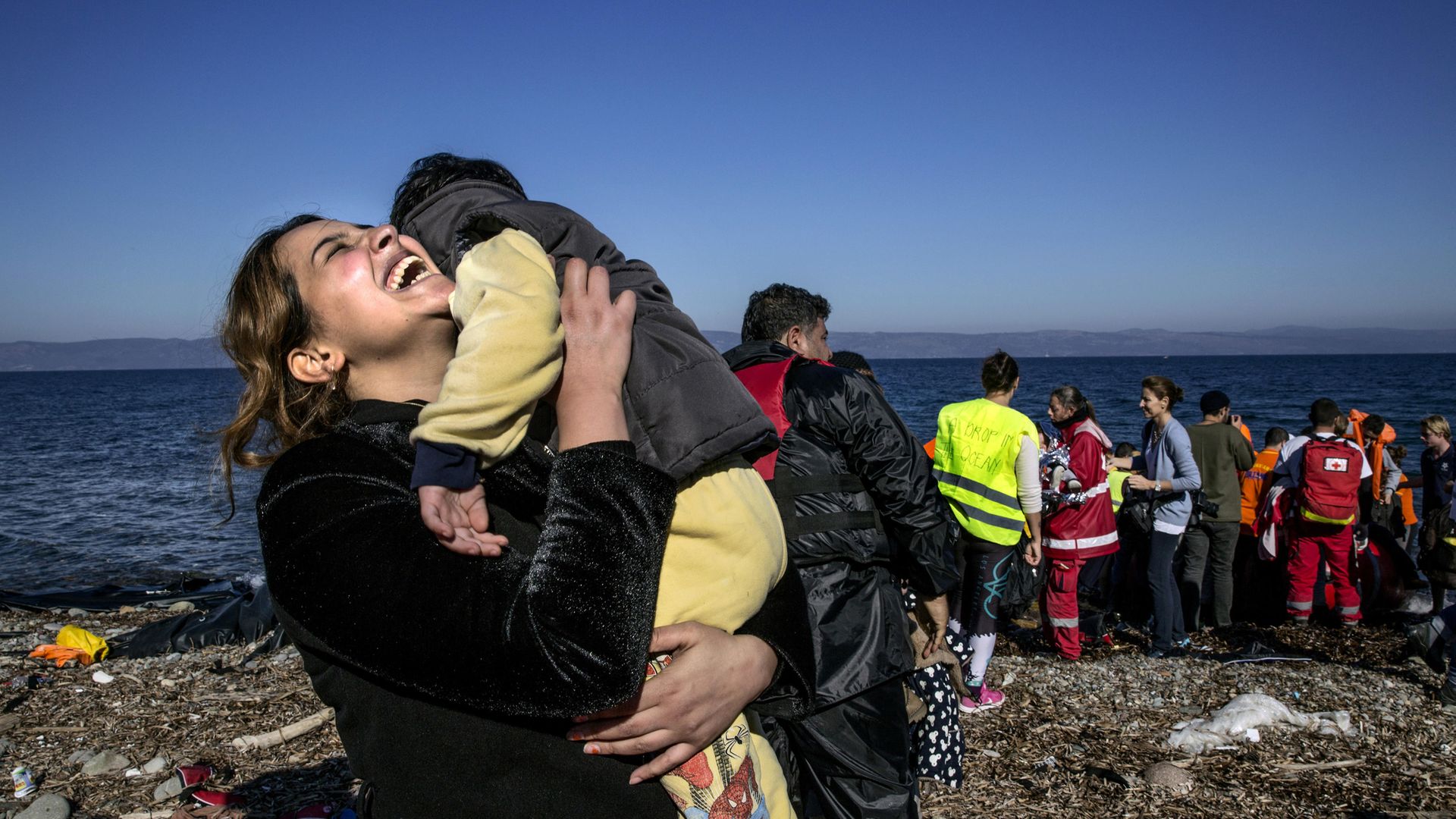 A Syrian refugee rejoices after arriving on an overcrowded raft to the island of Lesbos, Greece, in 2015 - Credit: Getty Images