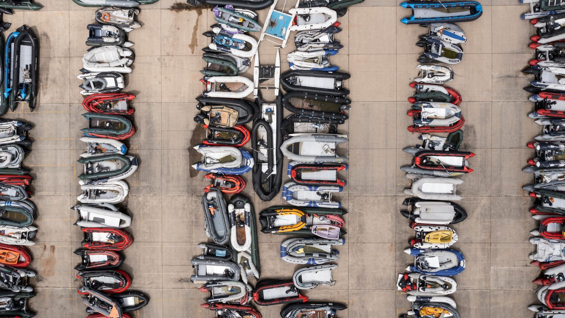 Inflatable dinghies used by migrants to cross the channel from France are stored in a compound in Dover, England - Credit: Getty Images