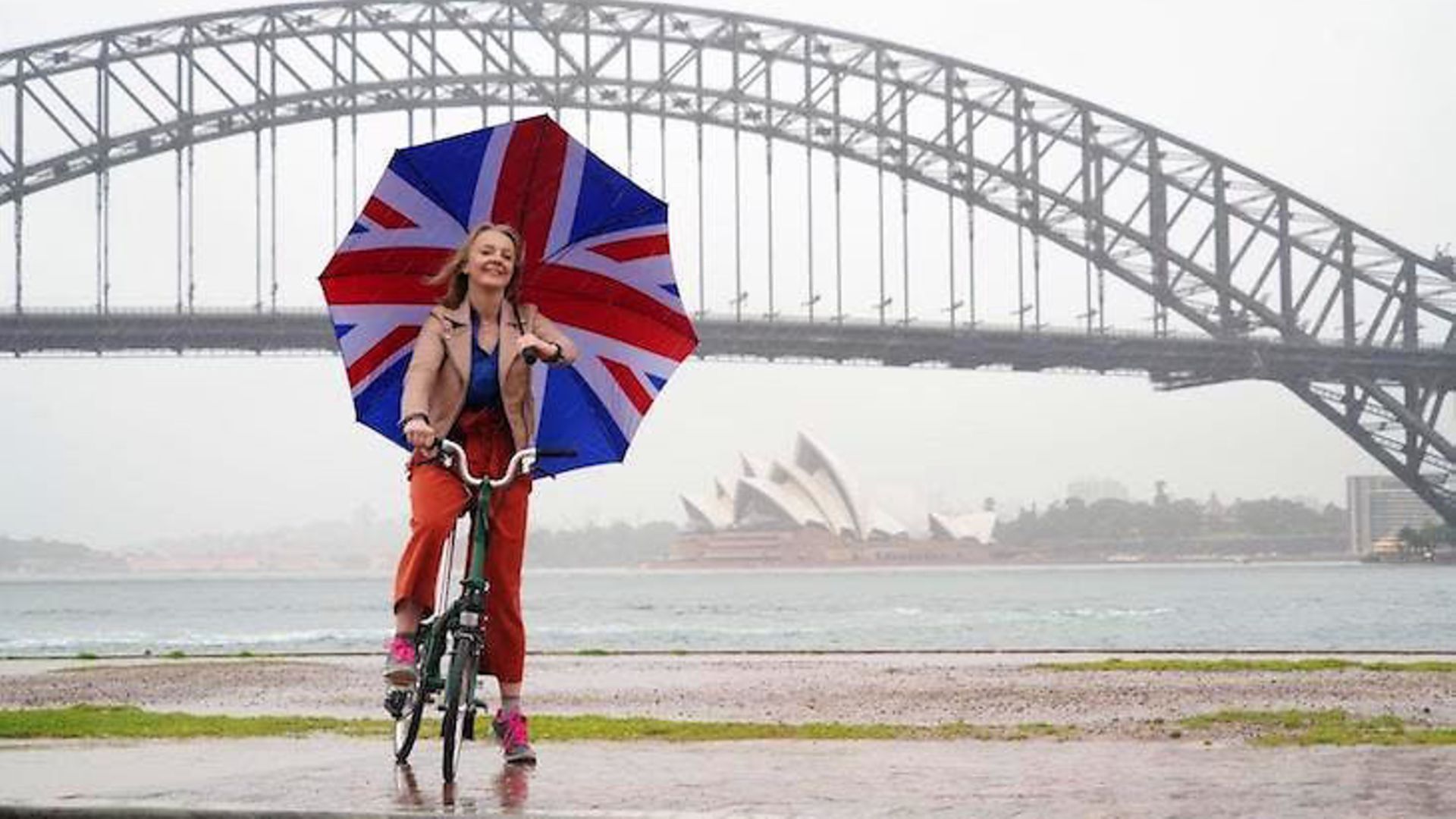 Liz Truss poses with a union flag umbrella as she takes visits Syndey to promote post-Brexit Britain - Credit: Twitter