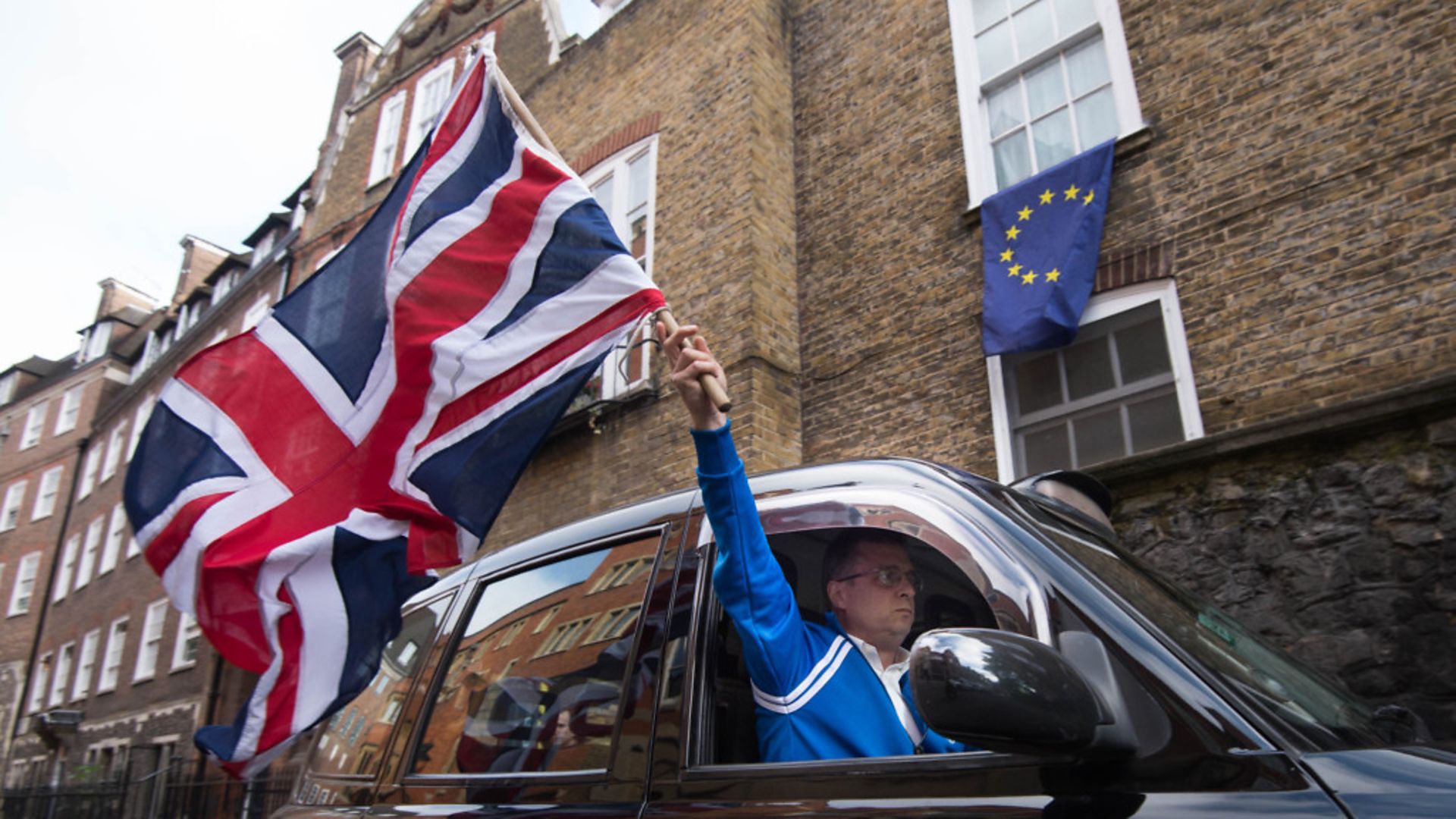 A London taxi driver waves a Union Jack flag in Westminster after the Brexit vote. Photo: PA.