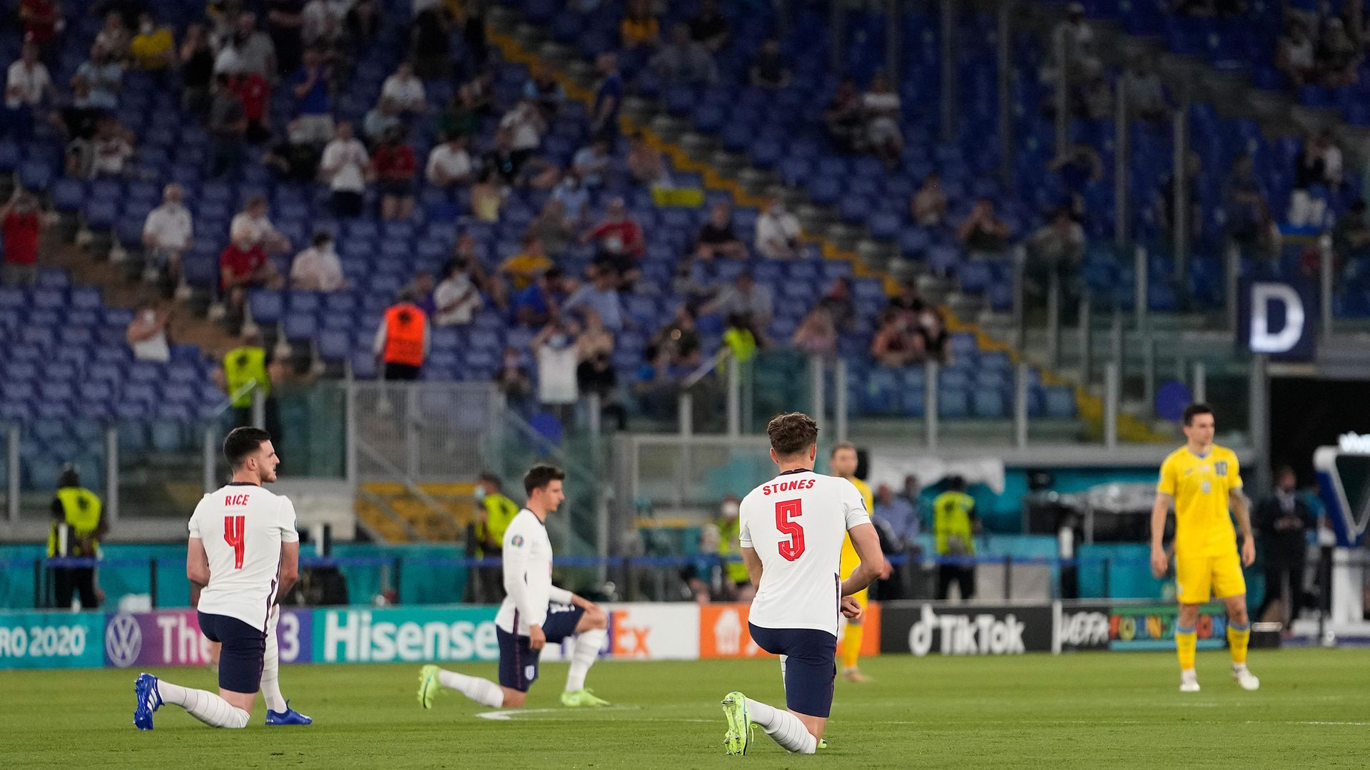 Declan Rice and John Stones of England take a knee while Ukraine players remain standing before their quarter-final - Credit: Photo by Alessandra Tarantino - Pool/Getty Images