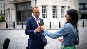 WhatsUp? Matt Hancock looks at the phone of his aide Gina Coladangelo as they leave the BBC in central London in June. Weeks later, news of the pair's affair - and Hancock's use of Gmail and WhatsApp for government business - emerged - Credit: AFP via Getty Images