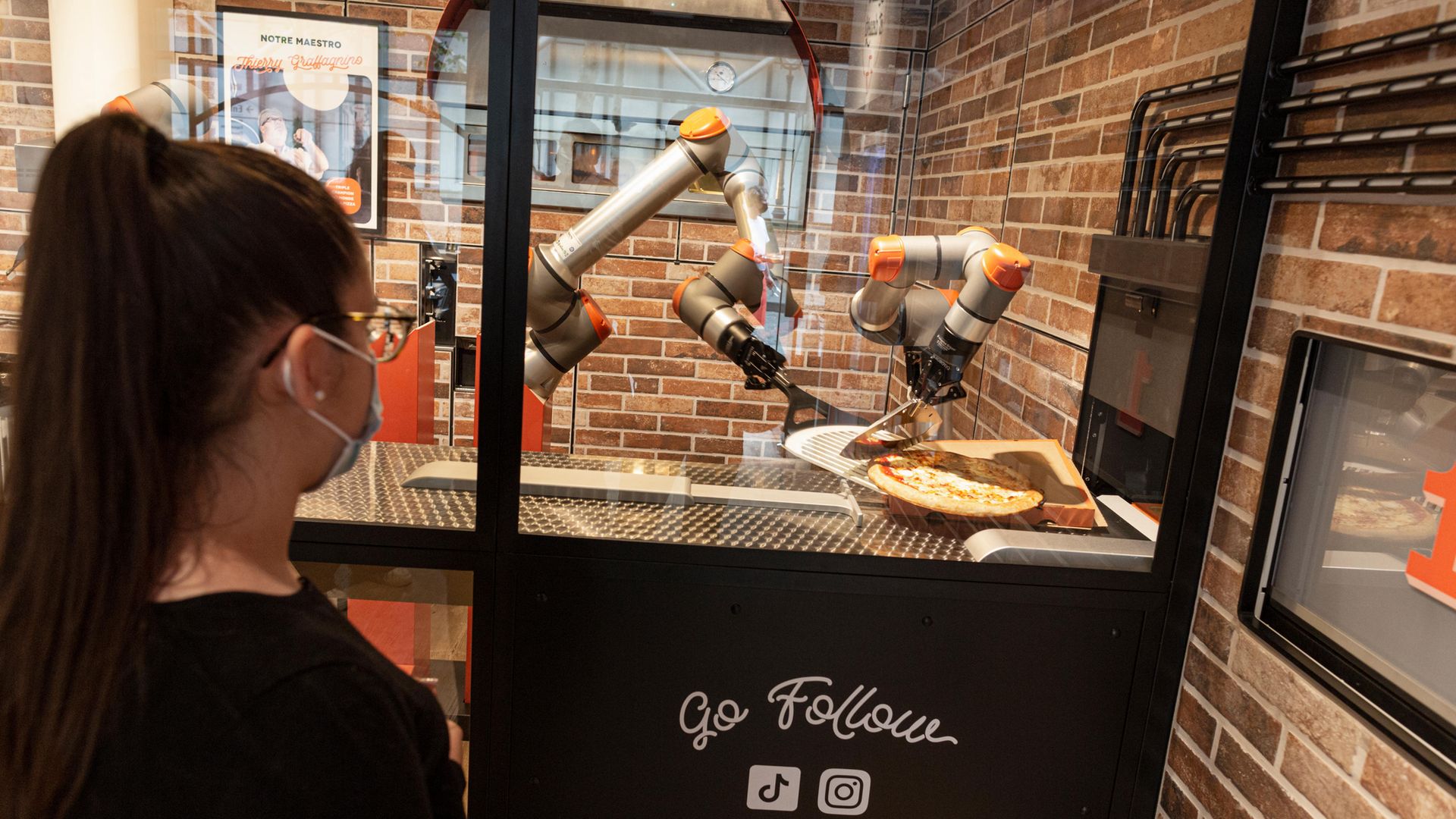 A woman watches as her pizza is prepared at Pazzi, Paris' first robotic pizzeria - Credit: Photo by Sam Tarling/Getty Images