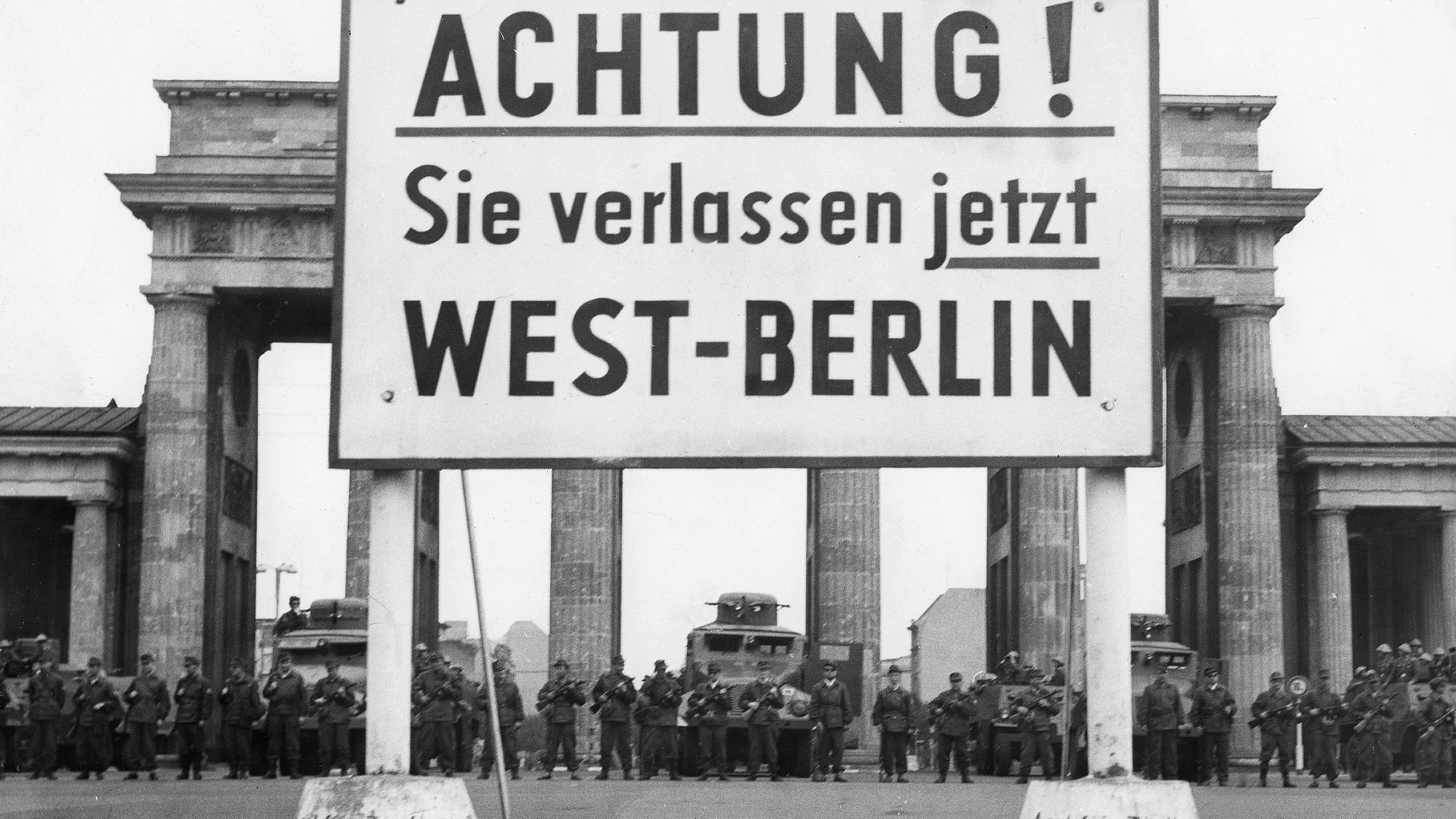 Guards at stand at the Brandenburg Gate, as the Berlin Wall goes up behind them, in August 1961 - Credit: ullstein bild via Getty Images