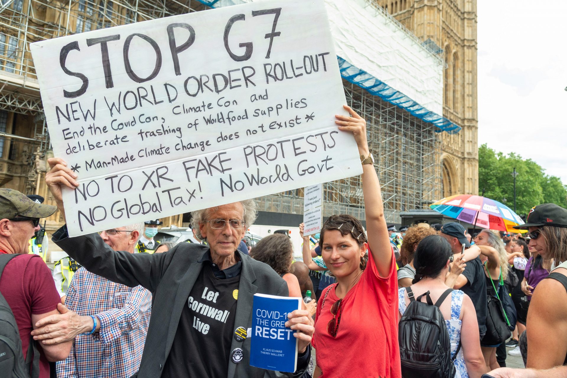 Piers Corbyn and a rallygoer hold a placard outside the Houses of Parliament. Photo: Dave Rushen/SOPA Images/LightRocket via Getty Images.