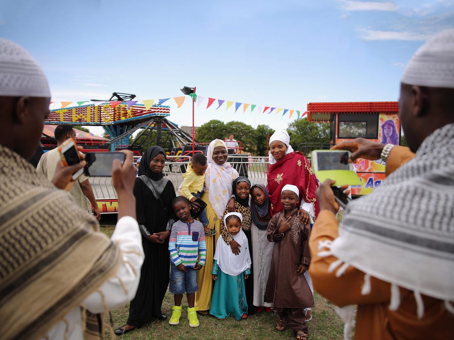 A family have their photograph taken after morning prayers during an Eid celebration in London’s Burgess Park. The Muslim holiday Eid marks the end of 30 days of dawn-to-sunset fasting during the holy month of Ramadan.  
Photo: Dan Kitwood/Getty Images.