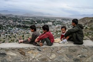 Children sit on a wall overlooking the city of Kabul, 2020. Credit: WAKIL KOHSAR/AFP via Getty.
