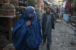 An burqa-clad Afghan woman walks through a market in Kabul. Photo: Hector Retamal/AFP via Getty Images.