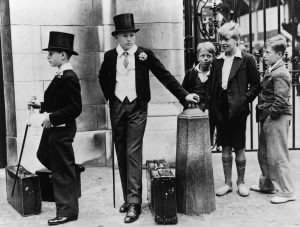 Local boys look on with amusement at Harrow schoolboys Peter Wagner (left) and Thomas Dyson in their formal uniform at the Eton vs Harrow cricket match at Lord's, July 1937. Photo: Jimmy Sime/Central Press/Hulton Archive/Getty Images