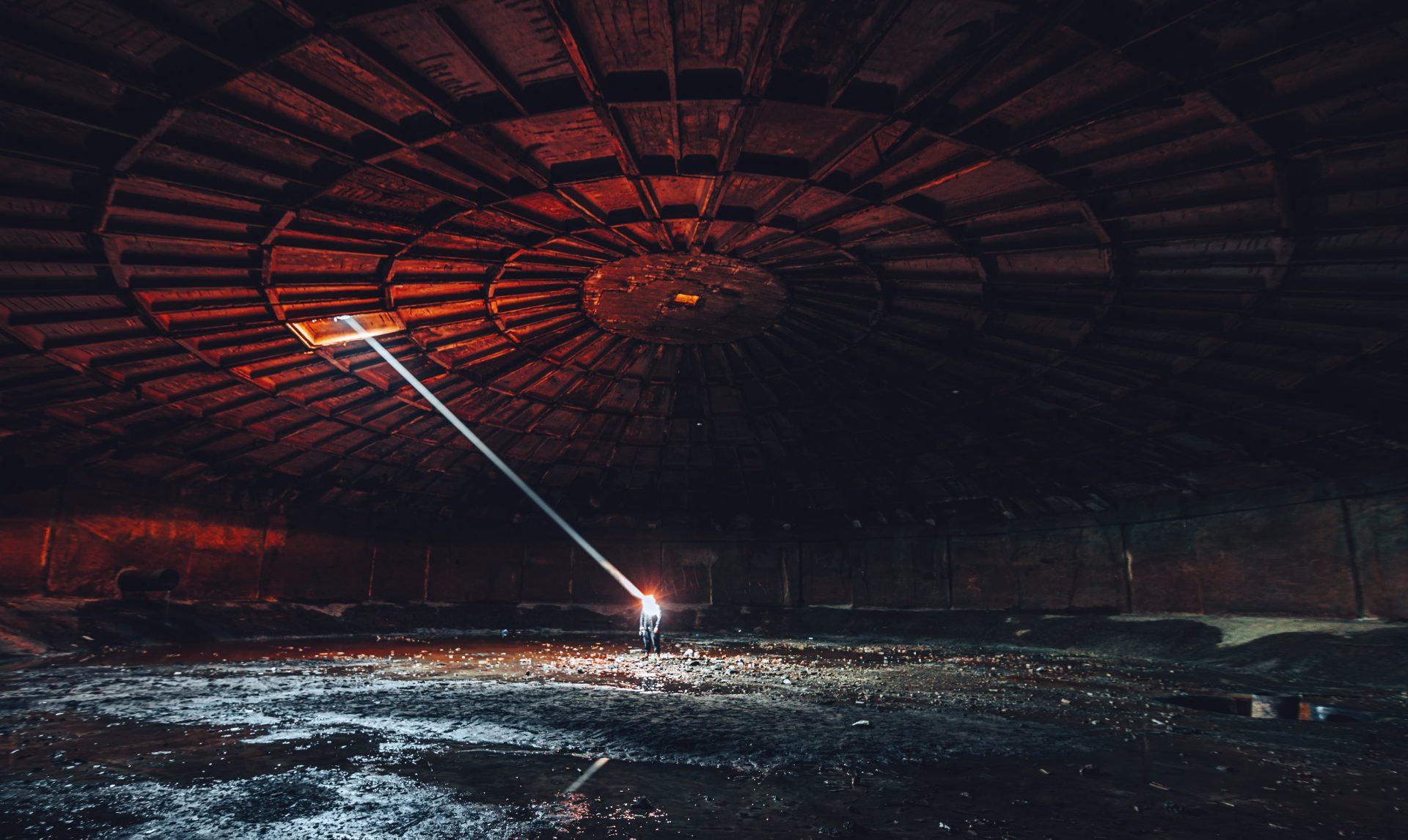 : An underground water reservoir in Tbilisi, with a shaft of light striking photographer Davit Tabagari.