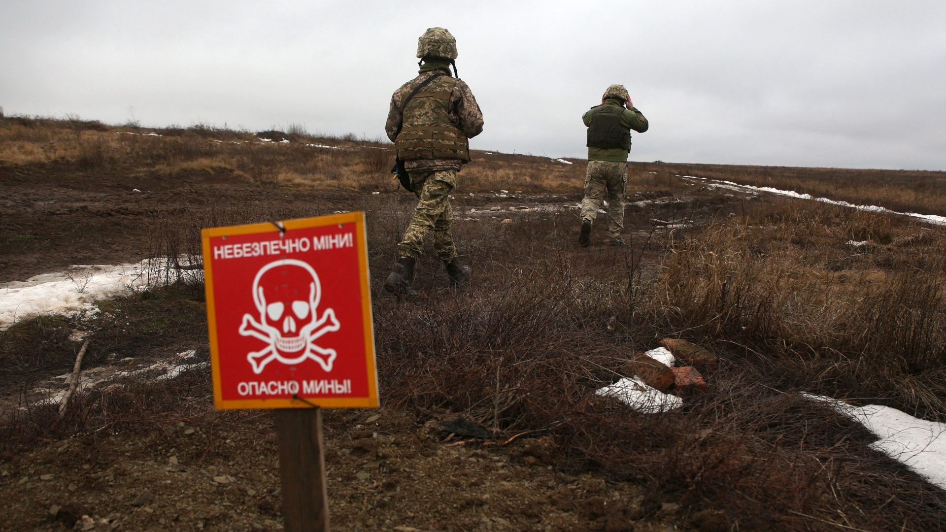 An Ukrainian Military Forces serviceman walk past a metal plate which reads as "Caution mines" on the frontline with Russia-backed separatists near Luganske village, in Donetsk region. Photo: ANATOLII STEPANOV/AFP via Getty Images