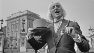 Jimmy Savile showing off his OBE. Photo: Leslie Lee/Daily Express/Hulton Archive/Getty Images.