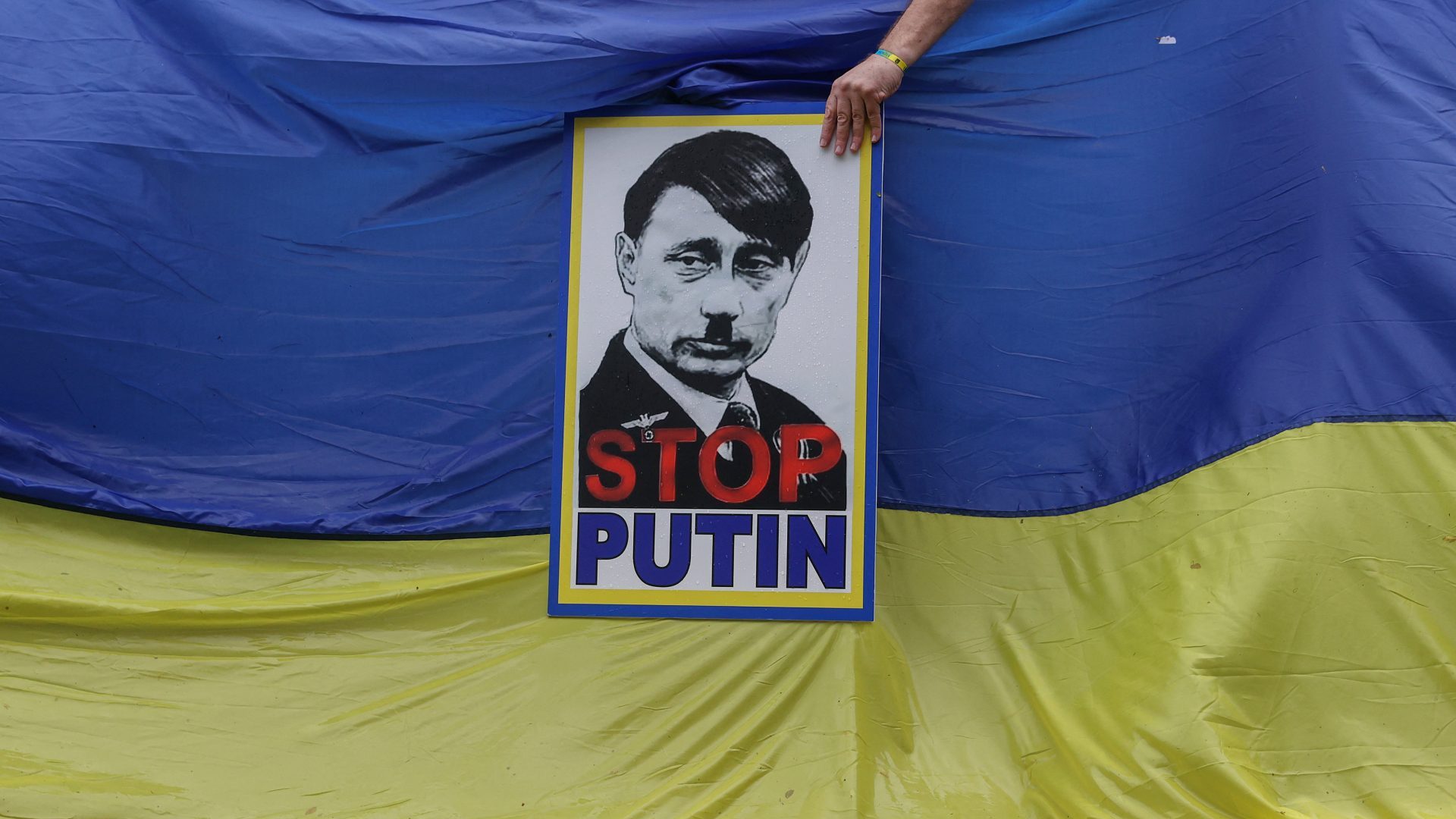A member of South Africa's Ukrainian Association holds a poster depicting Russian President Vladimir Putin as Adolf Hitler. Photo: PHILL MAGAKOE/AFP via Getty Images