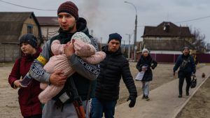 A Ukrainian volunteer fighter 
carries a child as he helps local 
residents of Irpin fleeing from the 
Russian advance. Photo: Marcus Yam/LA Times
