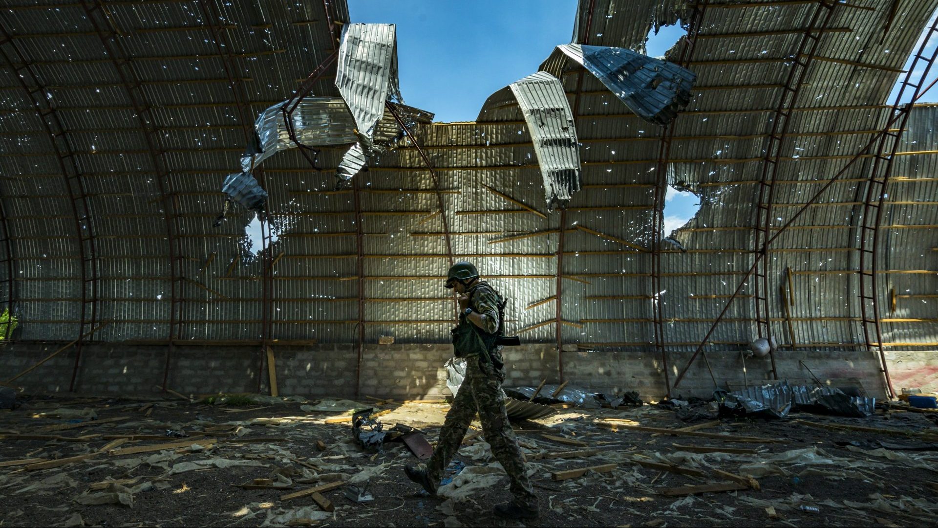 A Ukrainian soldier 
examines a barn 
destroyed by Russian shelling near the frontline in Zaporizhzhia province. Photo: Celestino Arce/NurPhoto/Getty