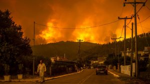 A local resident walks as a wildfire rages near the village of Gouves, on Euboea island, second largest Greek island, on August 8, 2021. - Hundreds of firefighters battled a blaze on the outskirts of Athens as several fires raged in Greece. Photo: ANGELOS TZORTZINIS/AFP via Getty Images