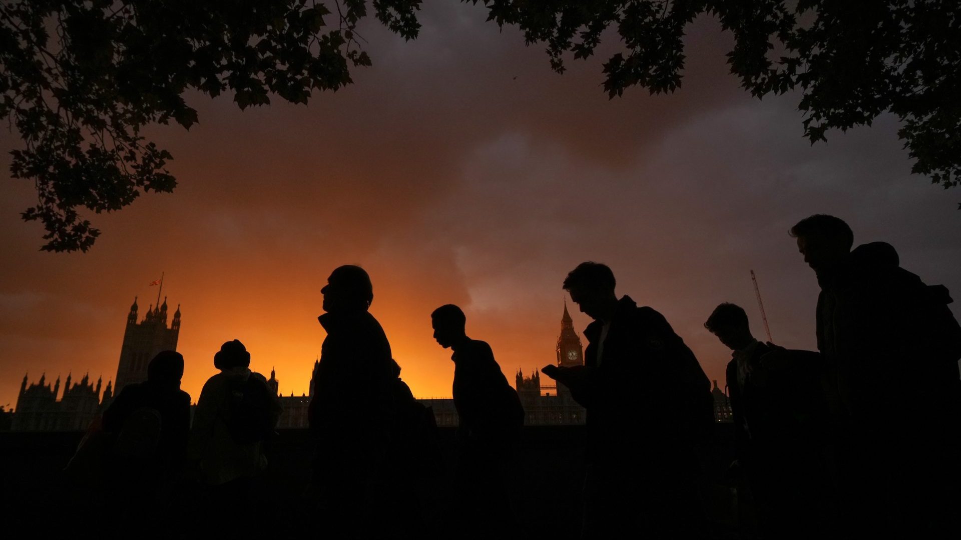 The sun sets behind the Houses of Parliament as people queue to see Queen Elizabeth lying in state. Photo: Christopher Furlong/
Getty