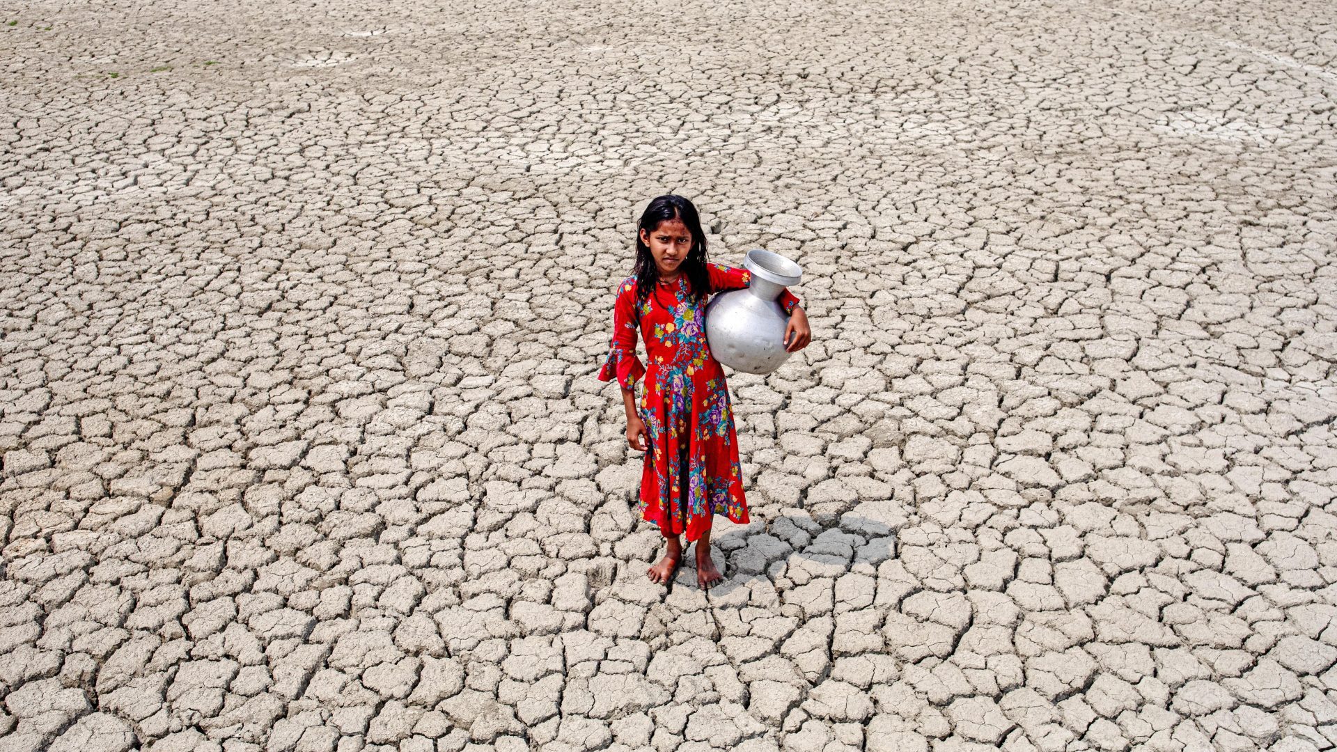 A girl walks into a deep cracks field after collecting drinking water from a pond near mangrove forest Sundarban in Satkhira, Bangladesh. Photo: Kazi Salahuddin Razu/NurPhoto via Getty Images