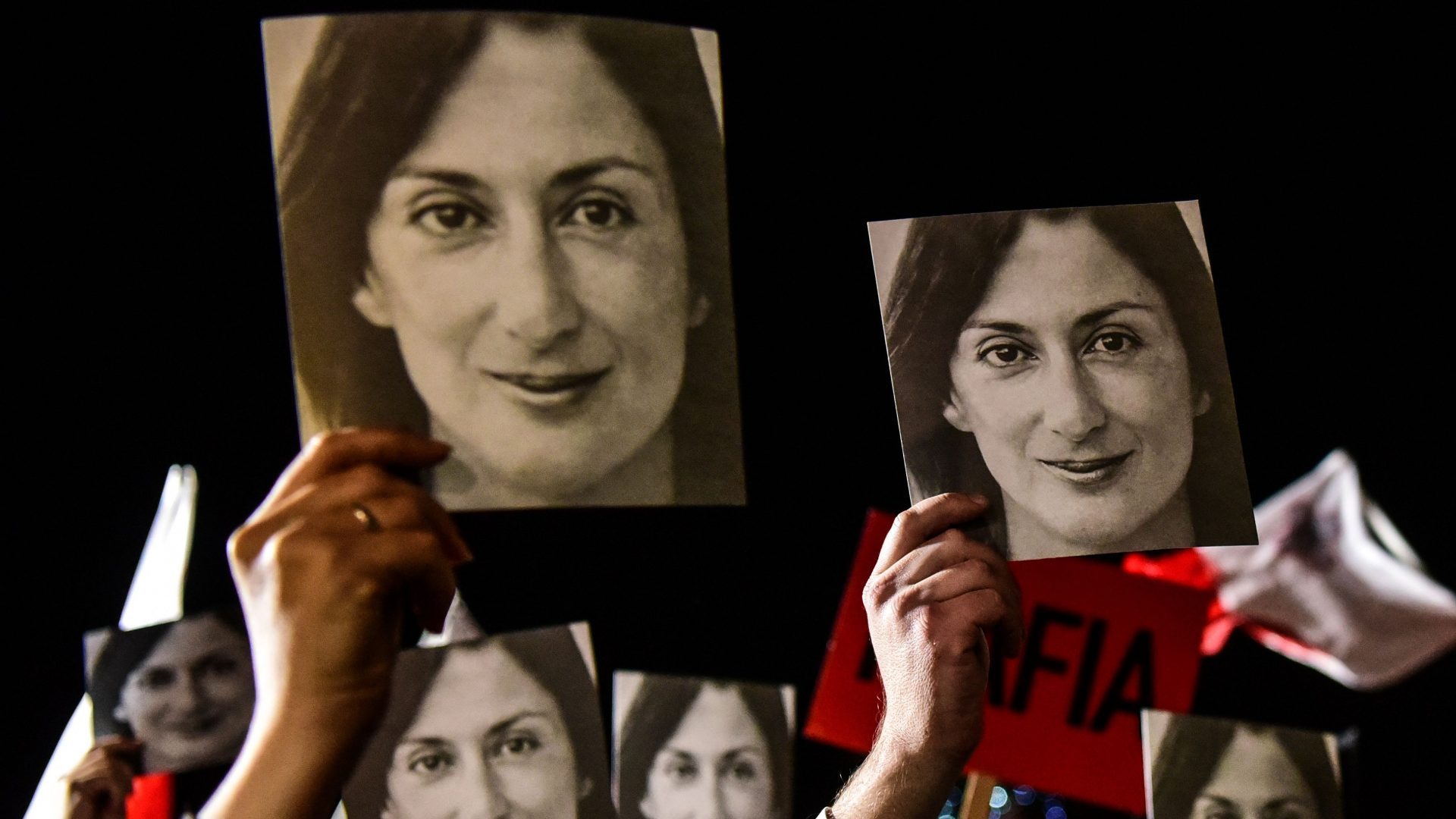 Protesters hold photos of killed journalist Daphne Caruana Galizia outside the office of the Maltese prime minister in 2019 (Photo by STRINGER/AFP via Getty Images)